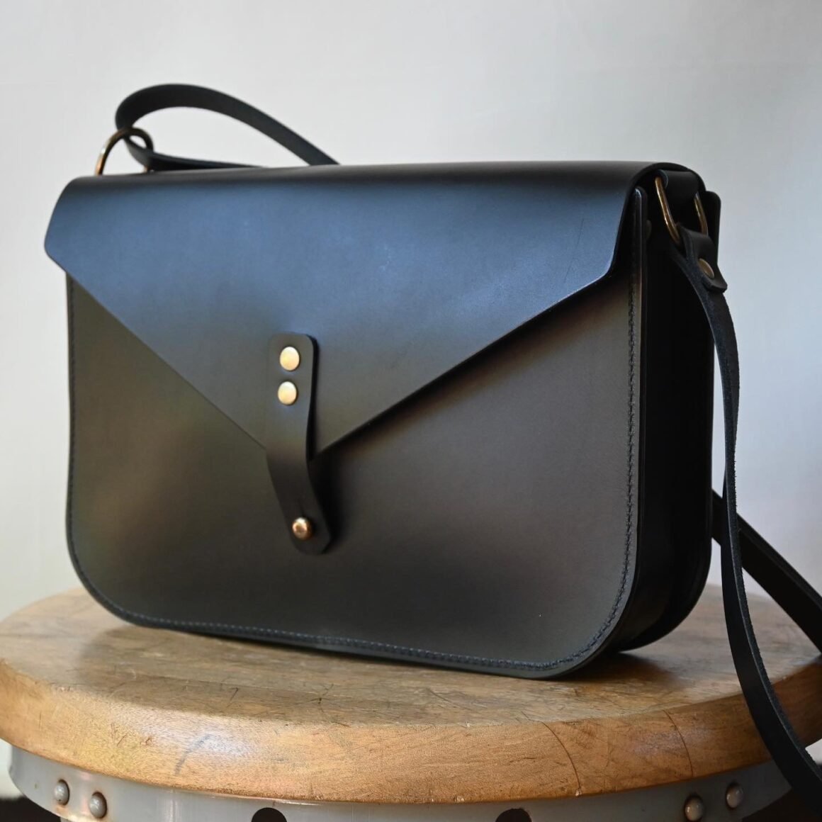 handmade black leather satchel bag with crossbody strap and brass hardware by Stitch and Rivet